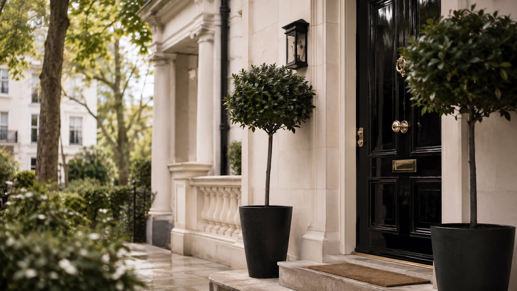 A glossy black townhouse front door with brass fittings and bay trees, Prime Central London
