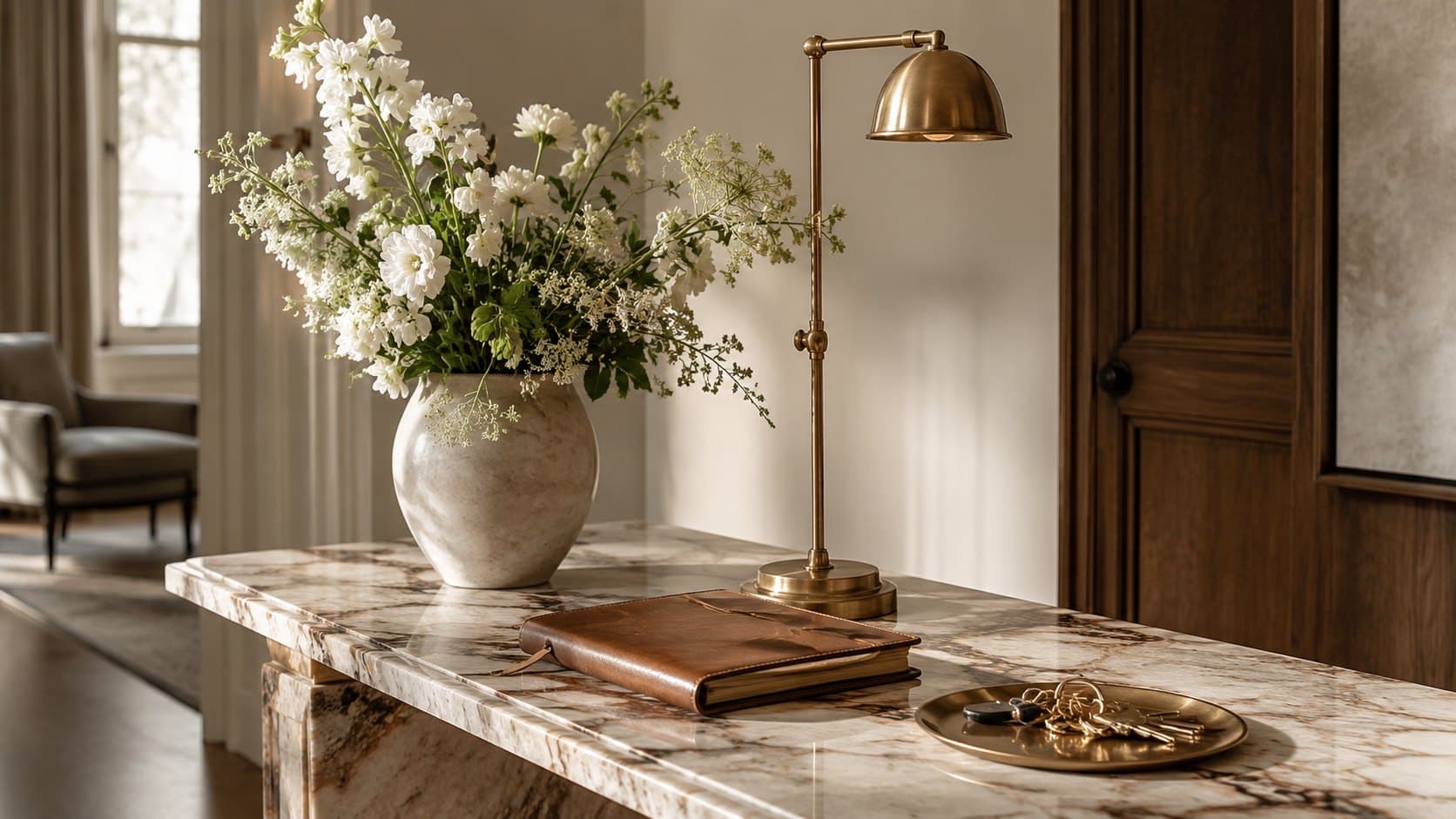 A marble console with fresh flowers, a brass lamp, a leather guest book and keys — boutique property management