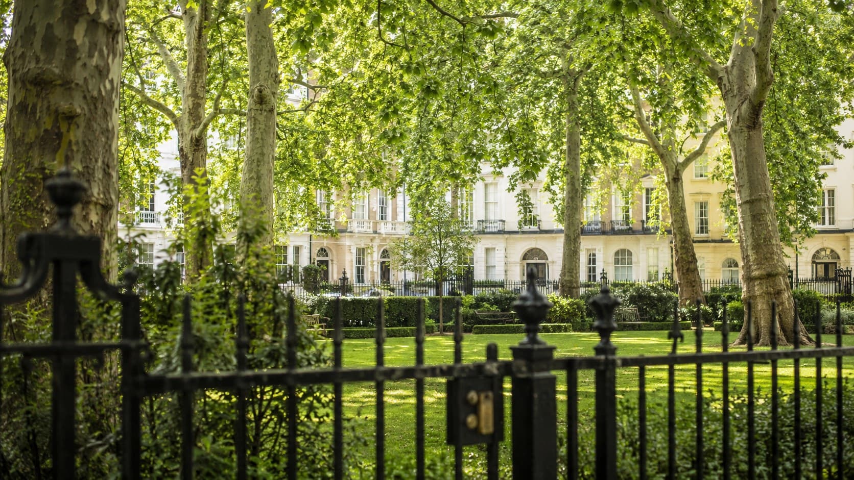 A leafy private London garden square behind iron railings